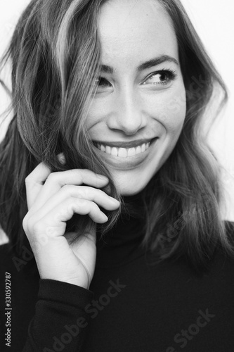 Portrait of a young cute girl in black and white touching her hair and looking to the side photo