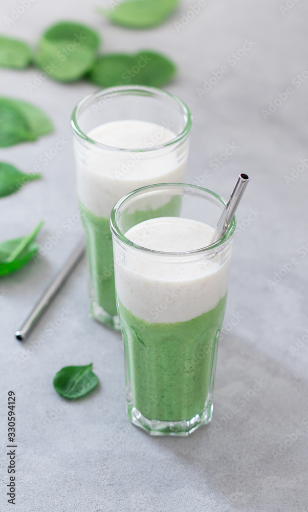 Green spinach smoothie with oatmeal smoothie in a glass on a light gray background Green spinach smoothie with oatmeal smoothie in a glass on a light gray background