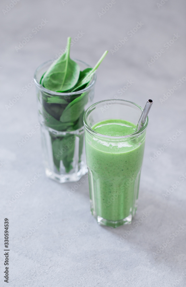 Fototapeta premium Spinach smoothie in a glass on a light background