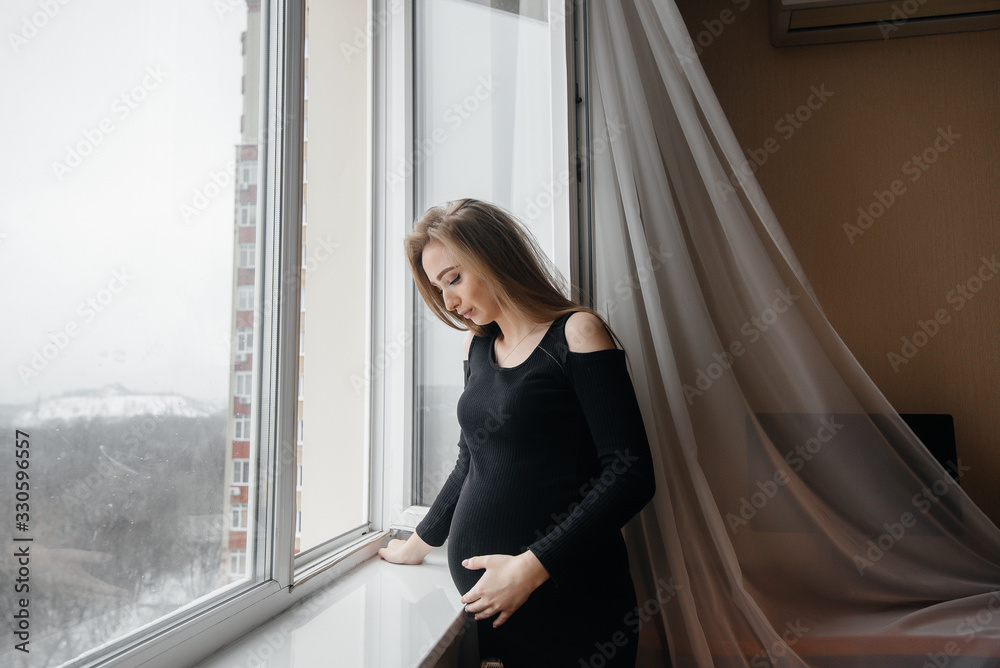A pregnant girl is breathing fresh air from the window A pregnant girl is breathing fresh air from the window