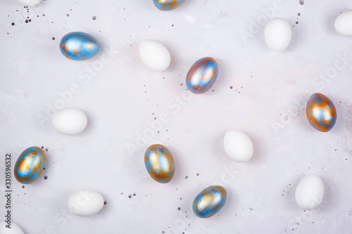Colored Easter eggs in blue and gold lie on gray background. Minimalistic holiday layout. Top view layout.