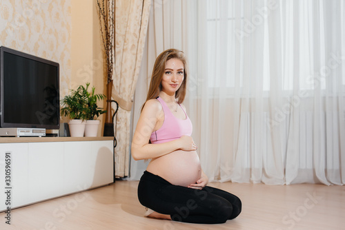 A pregnant girl does yoga at home. Health