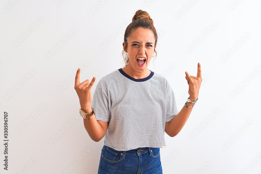 Young redhead modern woman wearing a bun over isolated background shouting with crazy expression doing rock symbol with hands up. Music star. Heavy concept. Young redhead modern woman wearing a bun over isolated background shouting with crazy expression doing rock symbol with hands up. Music star. Heavy concept.