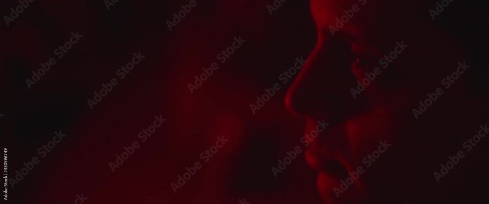 Profile of a young man with eyes wide open looking straight. Red lighting Profile of a young man with eyes wide open looking straight. Red lighting