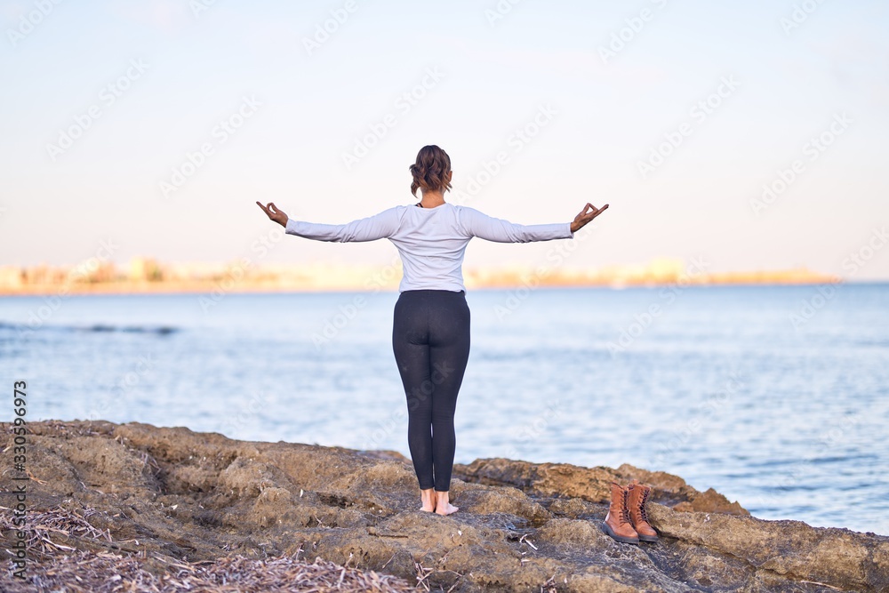 Young beautiful sportwoman practicing yoga. Coach teaching tree pose at the beach Young beautiful sportwoman practicing yoga. Coach teaching tree pose at the beach