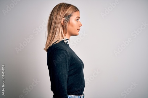 Foto Young beautiful blonde woman with blue eyes standing over white isolated background looking to side, relax profile pose with natural face with confident smile