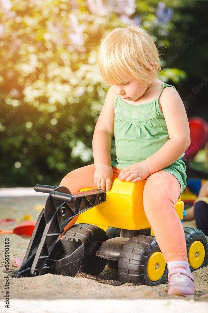 Child riding on a toy tractor on playground Child riding on a toy tractor on playground