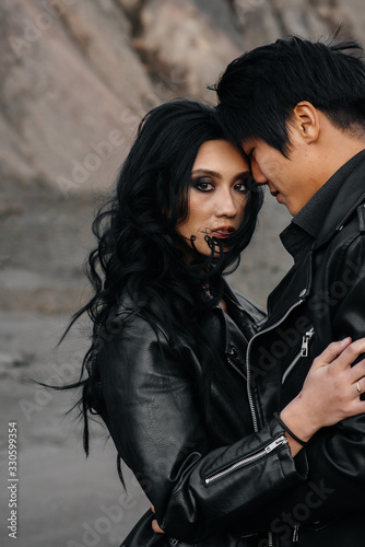 Woman and man in black clothes outdoors. Asiatics