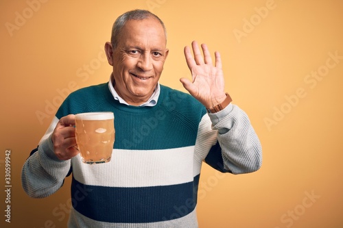 Bild auf Leinwand Senior handsome man drinking jar of beer standing over isolated yellow backgroun