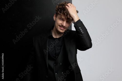 Cheerful fashion model fixing his hair and laughing