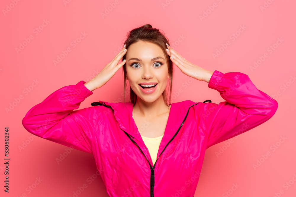 excited sportswoman touching head while looking at camera on pink background excited sportswoman touching head while looking at camera on pink background