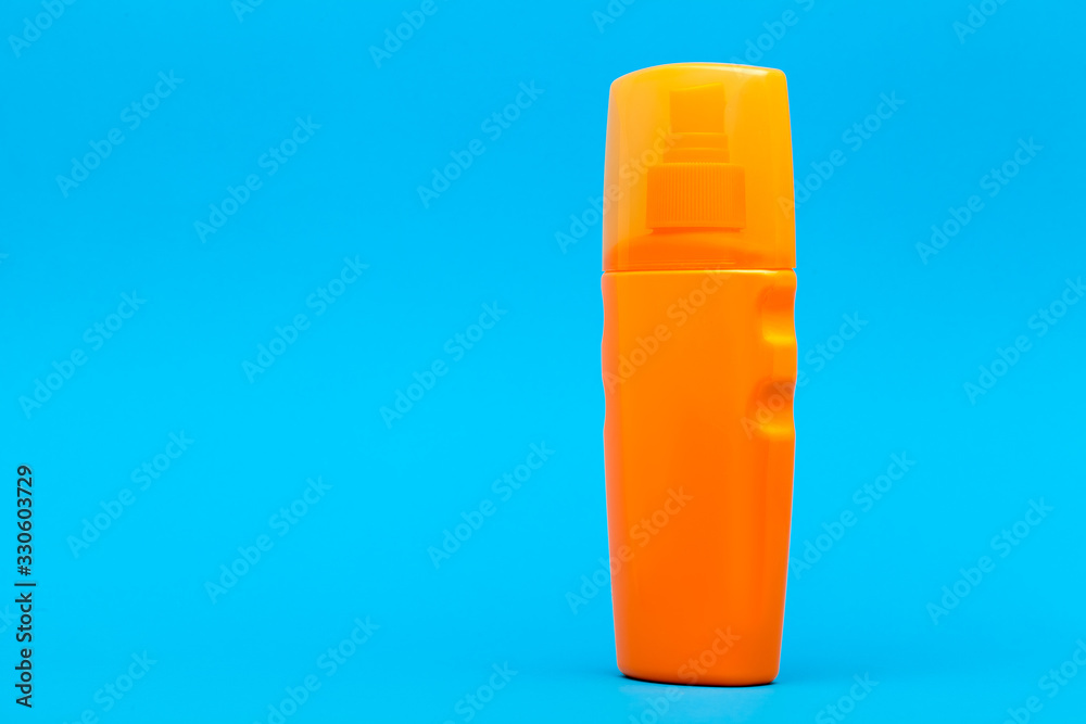 orange plastic bottle of suntan cream side view on a blue background with copy space. orange plastic bottle of suntan cream side view on a blue background with copy space.