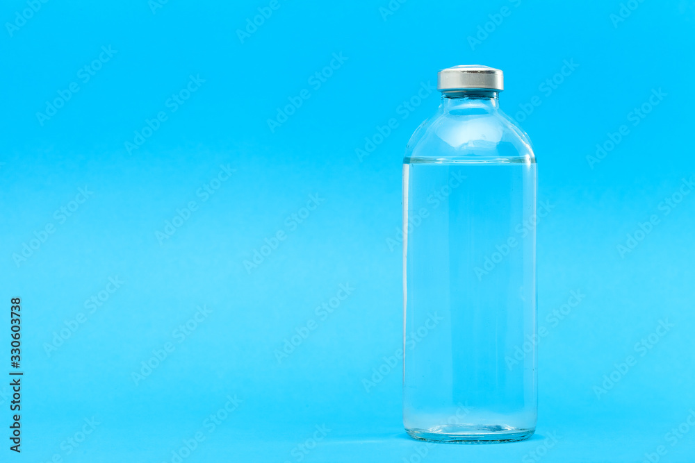 glass bottle with liquid for vaccination of patients for the treatment of health on a blue background with copy space. glass bottle with liquid for vaccination of patients for the treatment of health on a blue background with copy space.