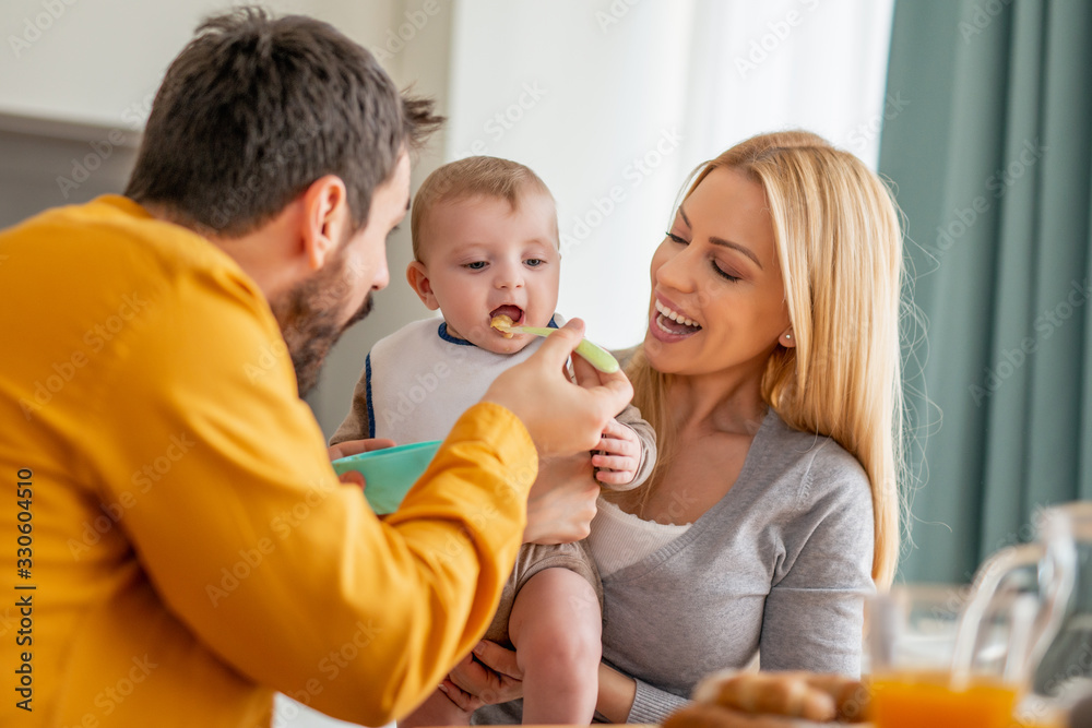 Father and mother feeding their little baby at home Father and mother feeding their little baby at home