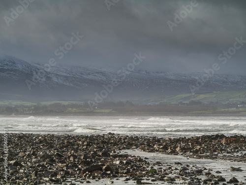 Strandhill beach at low tide, low cloudy sky, Mountains in the background covered with snow. Sligo county, Ireland.