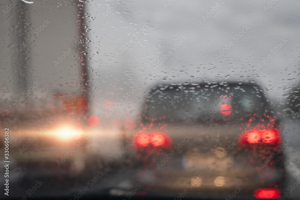 View from a car on a traffic jam on a rainy gloomy day, Raindrops on the glass in focus, commuters cars out of focus. Concept heavy urban traffic.
