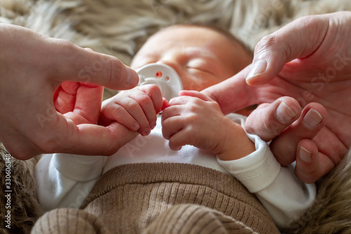 Vater und Mutter halten die Hände ihres Neugeborenen 