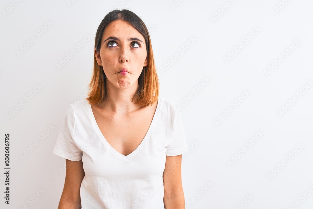 Beautiful redhead woman wearing casual white t-shirt over isolated background making fish face with lips, crazy and comical gesture. Funny expression. Beautiful redhead woman wearing casual white t-shirt over isolated background making fish face with lips, crazy and comical gesture. Funny expression.