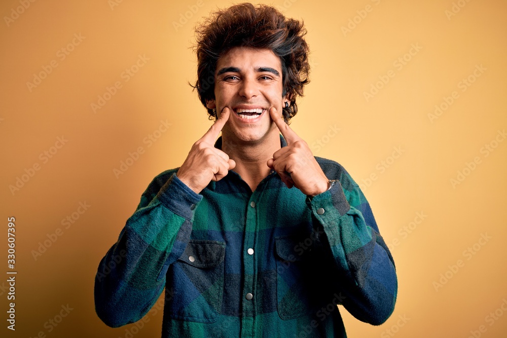 Young handsome man wearing casual shirt standing over isolated yellow background Smiling with open mouth, fingers pointing and forcing cheerful smile Young handsome man wearing casual shirt standing over isolated yellow background Smiling with open mouth, fingers pointing and forcing cheerful smile