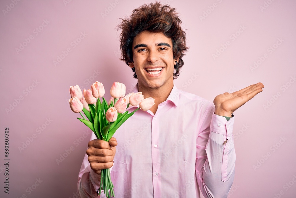 Young handsome man holding flowers standing over isolated pink background very happy and excited, winner expression celebrating victory screaming with big smile and raised hands Young handsome man holding flowers standing over isolated pink background very happy and excited, winner expression celebrating victory screaming with big smile and raised hands