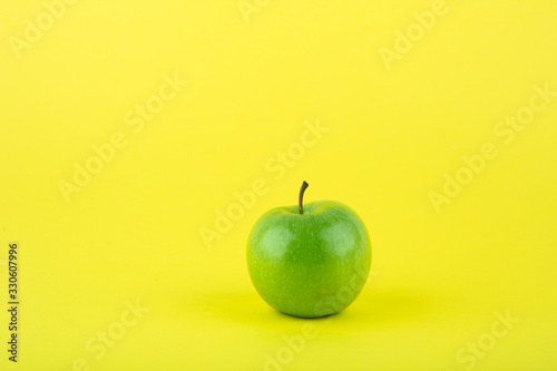 green apple on yellow background with copy space