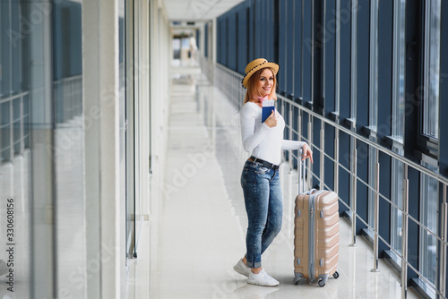 ready for the trip. Woman hold passport in hand with luggage on airport background. High season and vacation concept. Relax and lifestyles © Serhii