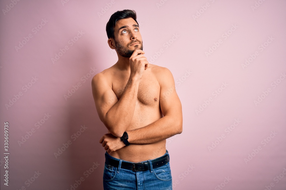 Young handsome strong man with beard shirtless standing over isolated pink background with hand on chin thinking about question, pensive expression. Smiling with thoughtful face. Doubt concept. Young handsome strong man with beard shirtless standing over isolated pink background with hand on chin thinking about question, pensive expression. Smiling with thoughtful face. Doubt concept.