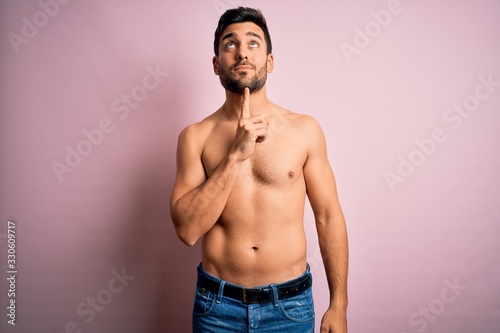 Obraz na plátně Young handsome strong man with beard shirtless standing over isolated pink backg