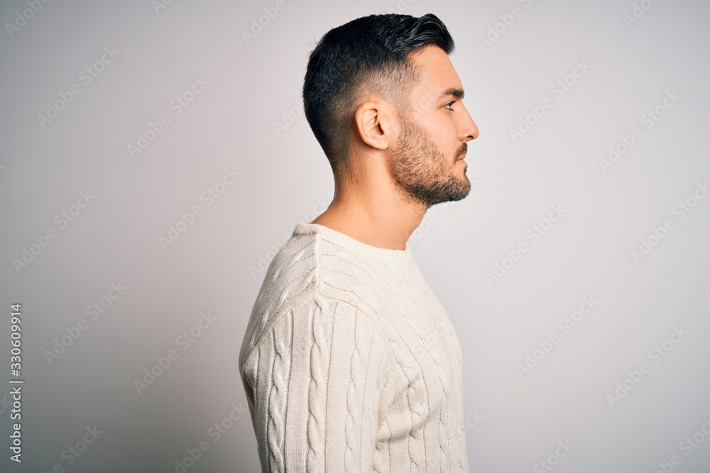 Young handsome man wearing casual sweater standing over isolated white background looking to side, relax profile pose with natural face with confident smile. Young handsome man wearing casual sweater standing over isolated white background looking to side, relax profile pose with natural face with confident smile.
