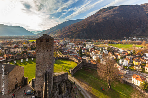 Stunning aerial panorama view of Bellinzona city from top of Castelgrande Castle ruin with beautiful sunshine, Swiss Alps with blue sky cloud in background, on sunny autumn day, Ticino, Switzerland