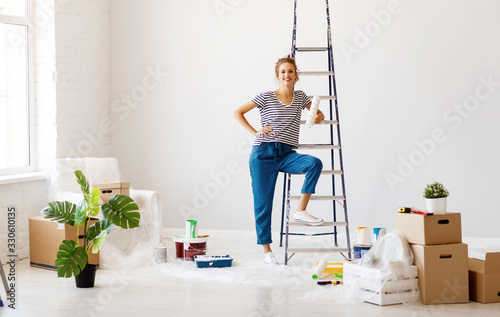 Repair in apartment. Happy young woman paints wall