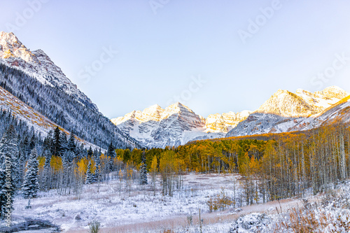 Maroon Bells peak sunrise sunlight in Aspen, Colorado rocky mountain and autumn yellow foliage panoramic view and winter snow frozen trees