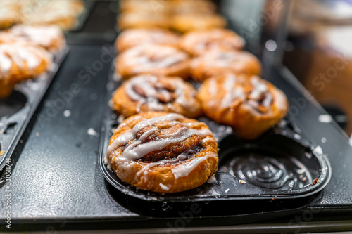 Closeup macro on bakery tray buffet for morning continental breakfast in hotel motel or office for sticky cinnamon roll buns with white icing