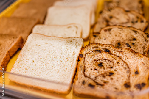 Assortment of bread with white, whole wheat and cinnamon raisin closeup on bakery tray buffet for morning continental breakfast in hotel motel or office