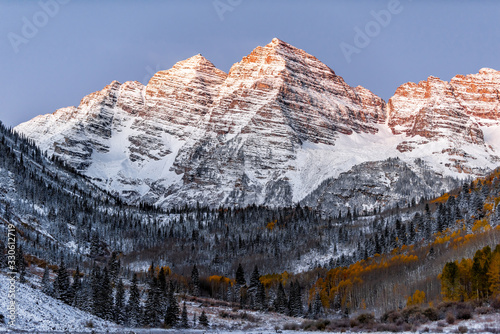 Maroon Bells morning sunrise with sunlight on peak in Aspen, Colorado rocky mountain and autumn yellow foliage view and winter snow