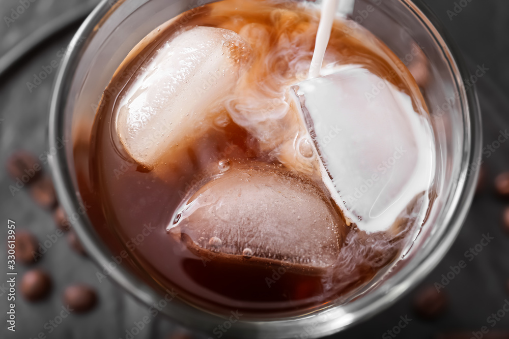 Pouring of milk into cold coffee in glass, closeup Pouring of milk into cold coffee in glass, closeup