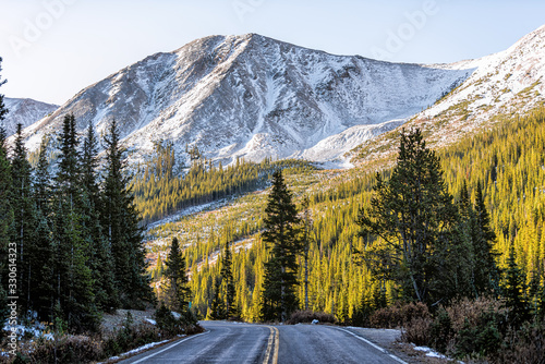 Independence Pass snow rocky mountain view and paved road scenic byway in morning sunrise near Aspen, Colorado in green autumn winter
