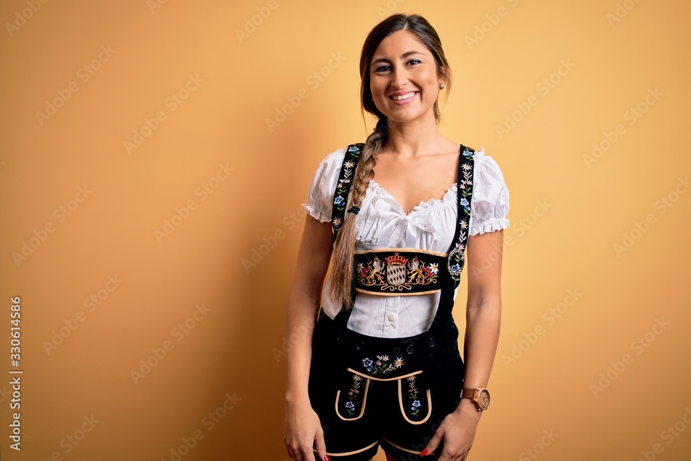 Young beautiful brunette german woman celebrating Octoberfest wearing traditional dress with a happy and cool smile on face. Lucky person. Young beautiful brunette german woman celebrating Octoberfest wearing traditional dress with a happy and cool smile on face. Lucky person.