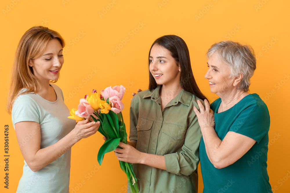 Mature woman with her adult daughter, mother and beautiful flowers on color background Mature woman with her adult daughter, mother and beautiful flowers on color background