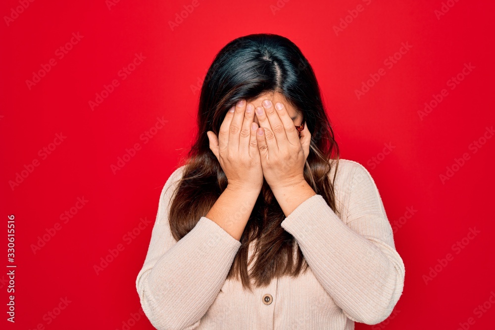 Young hispanic smart woman wearing glasses standing over red isolated background with sad expression covering face with hands while crying. Depression concept. Young hispanic smart woman wearing glasses standing over red isolated background with sad expression covering face with hands while crying. Depression concept.