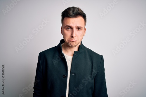 Young handsome business mas wearing elegant winter coat standing over isolated background depressed and worry for distress, crying angry and afraid. Sad expression.