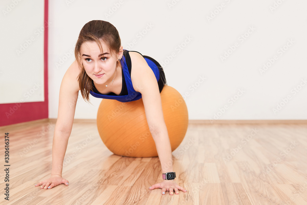 young woman is training by doing push up with exercise ball in gym young woman is training by doing push up with exercise ball in gym