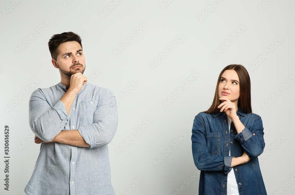 Pensive couple on light background. Thinking about answer for question - obrazy, fototapety, plakaty 