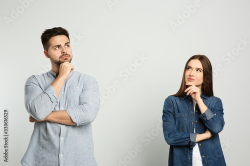 Pensive couple on light background. Thinking about answer for question photo
