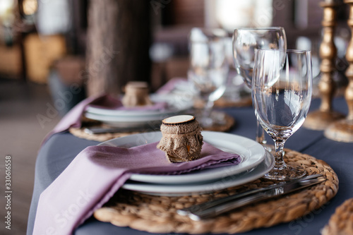 Festive table setting. Glass for the wine, white round plates and cutlery at a festive table, close-up. Side view