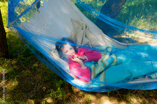 Canvastavla Child girl relaxing in a sunny hammock with mosquito net in forest