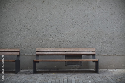 Closeup shot of wooden benches against a grey stone wall in an empty street