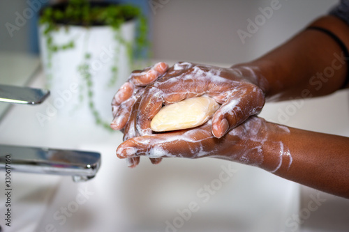 close up of black african australian woman washing hands with soap in sink