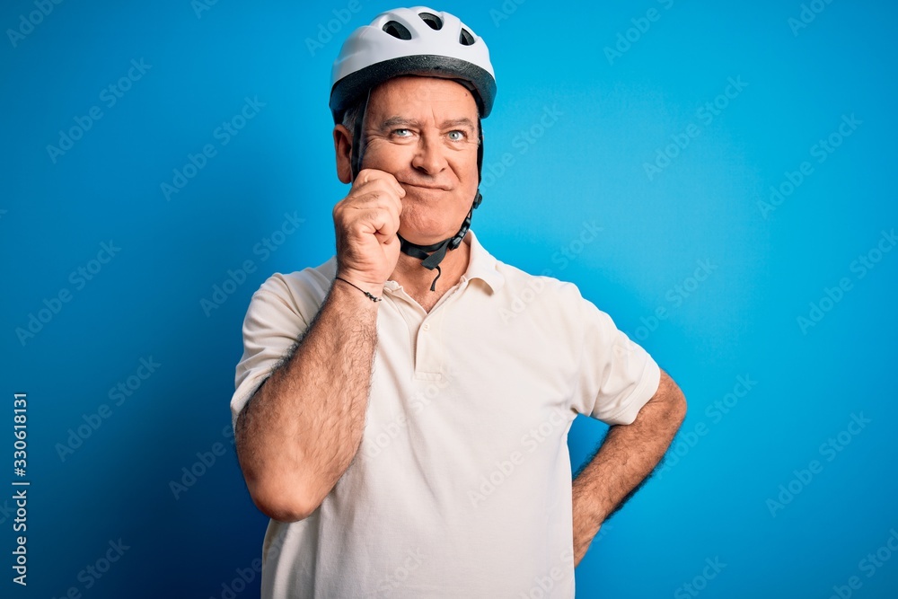 Middle age hoary cyclist man wearing bike security helmet over isolated blue background with hand on chin thinking about question, pensive expression. Smiling with thoughtful face. Doubt concept. Middle age hoary cyclist man wearing bike security helmet over isolated blue background with hand on chin thinking about question, pensive expression. Smiling with thoughtful face. Doubt concept.