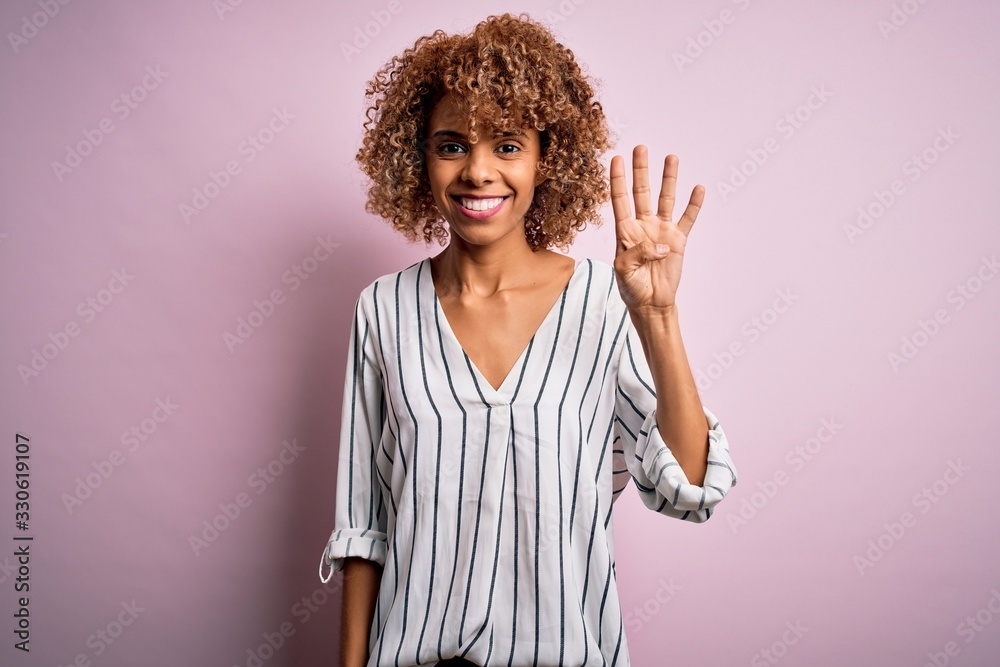 Beautiful african american woman with curly hair wearing striped t-shirt over pink background showing and pointing up with fingers number four while smiling confident and happy. Beautiful african american woman with curly hair wearing striped t-shirt over pink background showing and pointing up with fingers number four while smiling confident and happy.